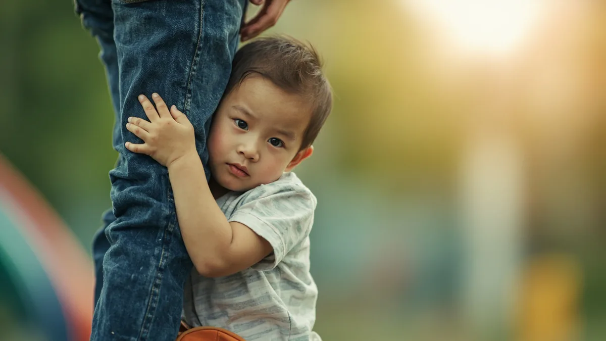A child clings to a parent, unwilling to leave a fun park, illustrating “unwilling to part or leave” in Chinese: 恋恋不舍 (liàn liàn bù shě)