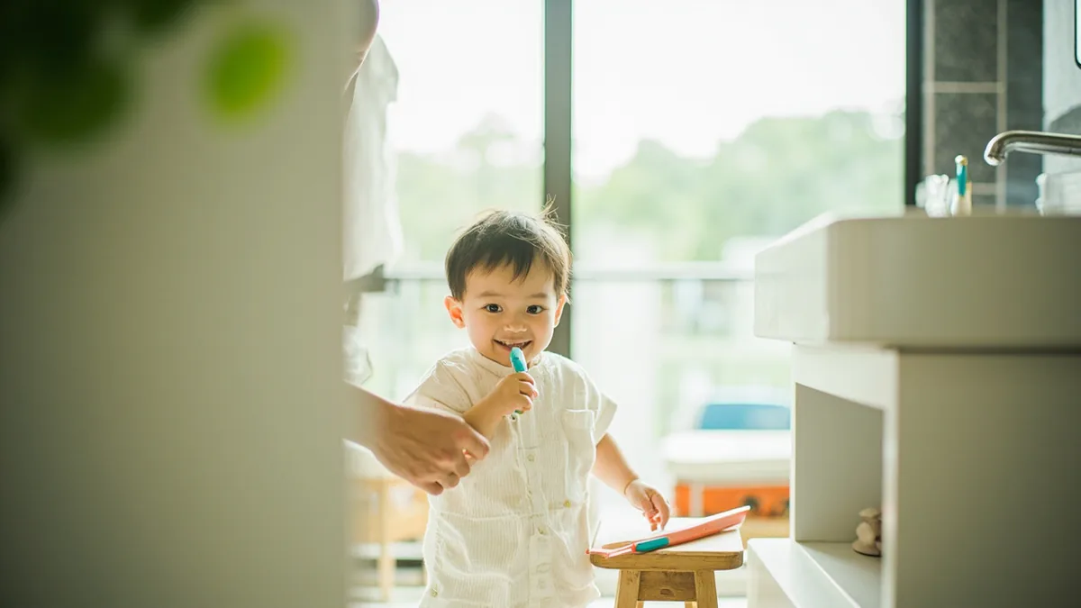 A child happily brushes their teeth in a bathroom, illustrating “brush your teeth” in Chinese: 刷牙 (shuāyá)