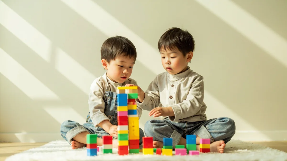Two children intently build a tower with colorful blocks, illustrating “build with blocks” in Chinese: 搭积木 (dā jīmù)