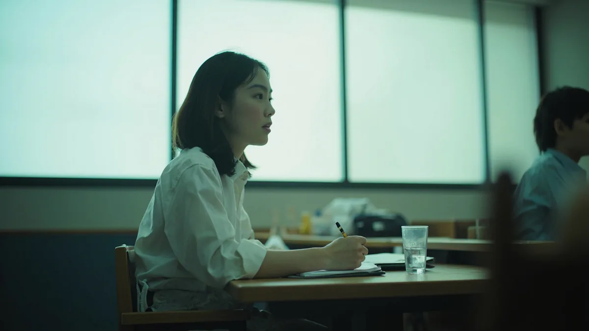 A student sits attentively in a classroom during a lecture, illustrating “course” in Chinese: 课程 (kèchéng)
