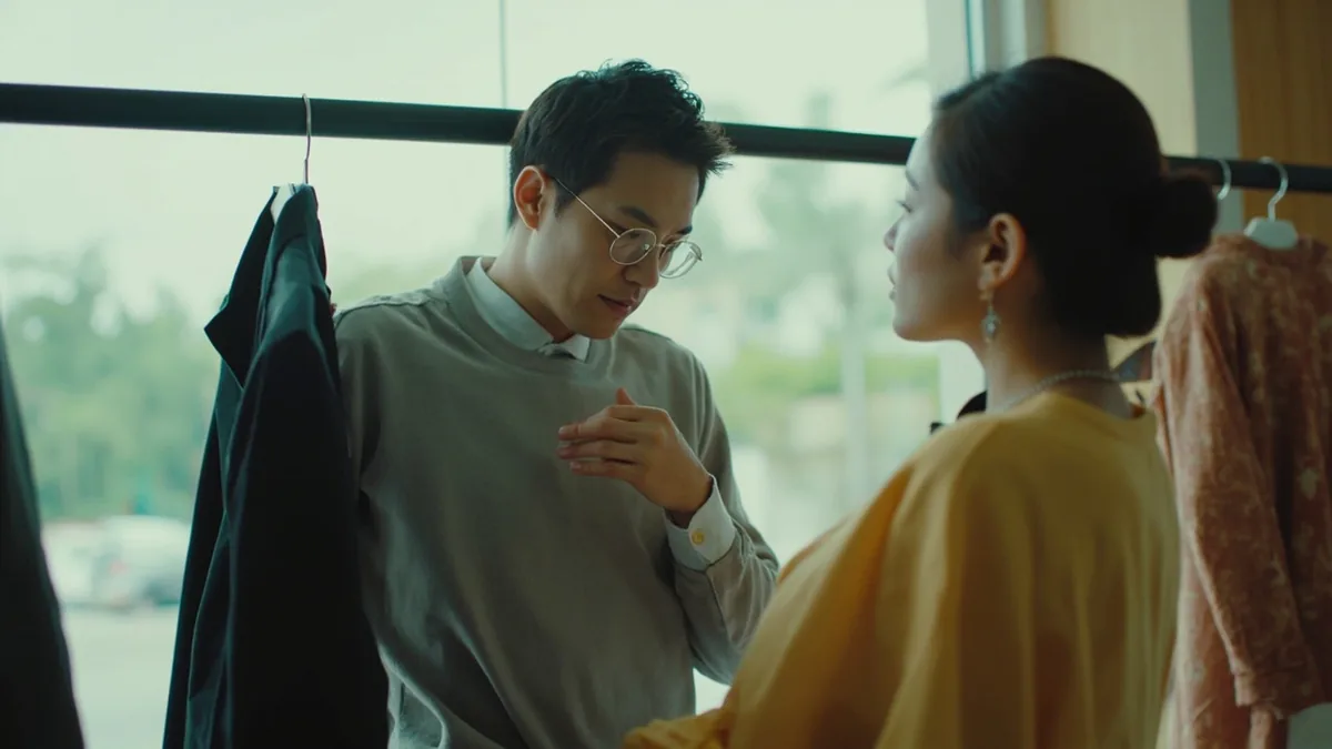 A person tries on a jacket and asks for a smaller size, illustrating “do you have a smaller size” in Chinese: 有小一号的吗？ (yǒu xiǎo yī hào de ma?)