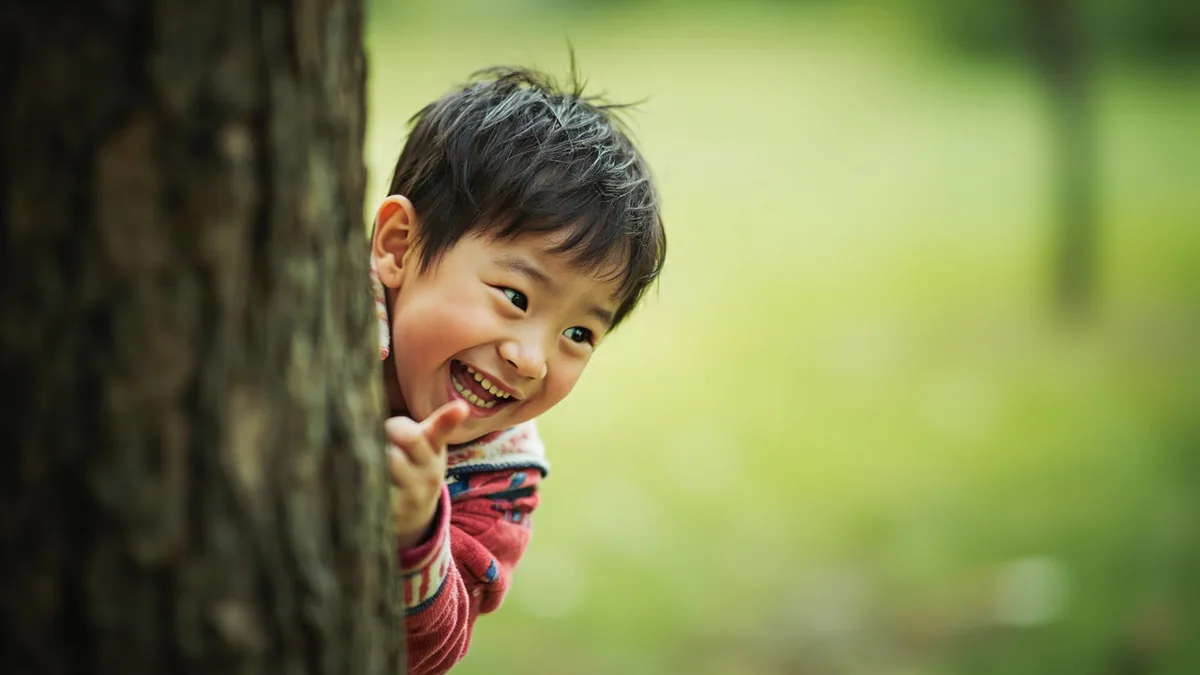 A child joyfully discovers a friend in a game, illustrating “found you” in Chinese: 我找到你啦 (wǒ zhǎodào nǐ la)