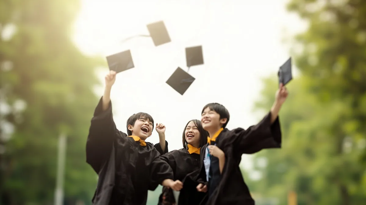 Recent graduates joyfully toss their caps into the air, illustrating “june” in Chinese: 六月 (liù yuè)