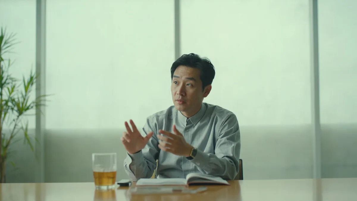 A team member prepares to present a progress update during a meeting, illustrating “let me report on our progress” in Chinese: 我汇报一下进展 (wǒ huìbào yīxià jìnzhǎn)
