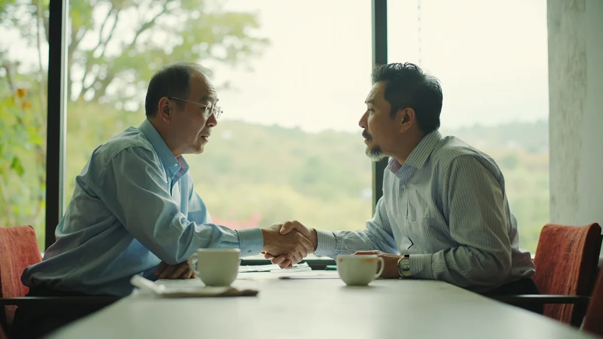 Two community leaders shake hands after resolving a long disagreement, illustrating “sign peace” in Chinese: 达成和平 (dáchéng hépíng)