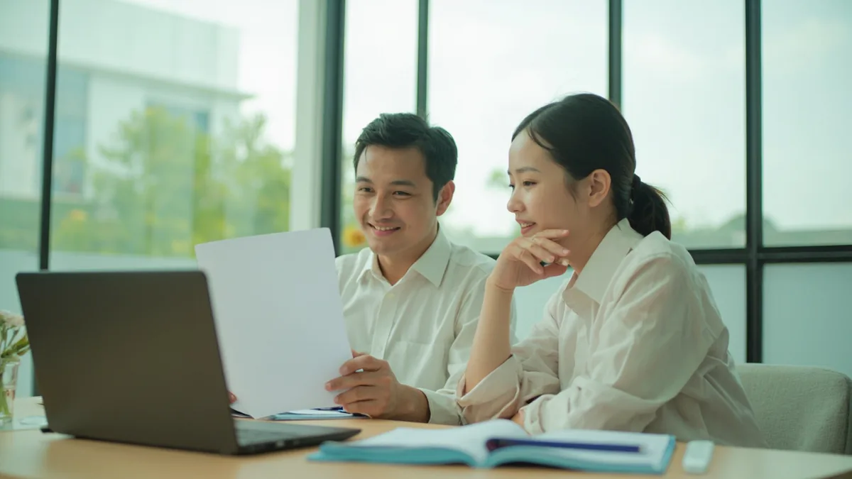 A team leader smiles while reviewing a successful project with a colleague, illustrating “the client is very satisfied” in Chinese: 客户很满意 (kèhù hěn mǎnyì)
