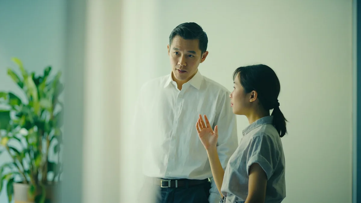 A young professional updates a colleague about a schedule change, illustrating “the meeting has been rescheduled” in Chinese: 会议改时间了 (huìyì gǎi shíjiān le)