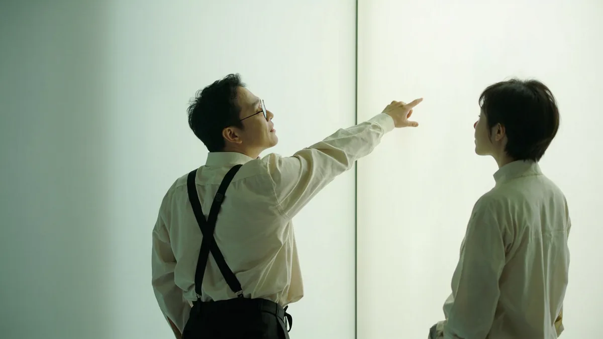 A helpful person points to an information panel for a visitor, illustrating “there's a Chinese explanation here” in Chinese: 这边有中文说明 (zhèbiān yǒu zhōngwén shuōmíng)