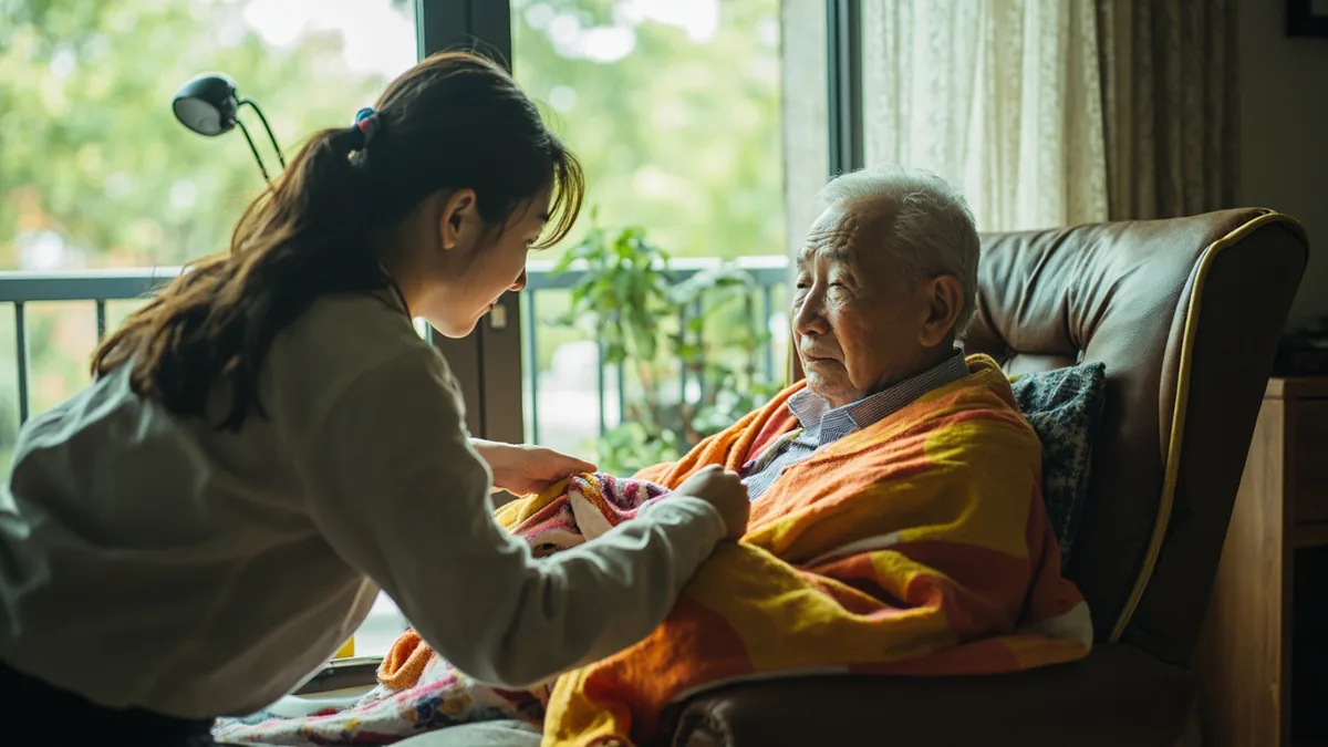 A young person helps an elderly relative with a comfortable blanket, illustrating “wishing you good health” in Chinese: 祝你身体健康 (zhù nǐ shēntǐ jiànkāng)
