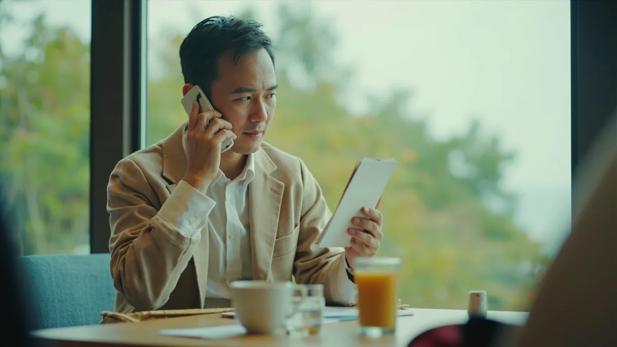 A person on the phone gestures, offering to take a message for a caller, illustrating “would you like to leave a message” in Chinese: 需要留言吗？ (xūyào liúyán ma?)