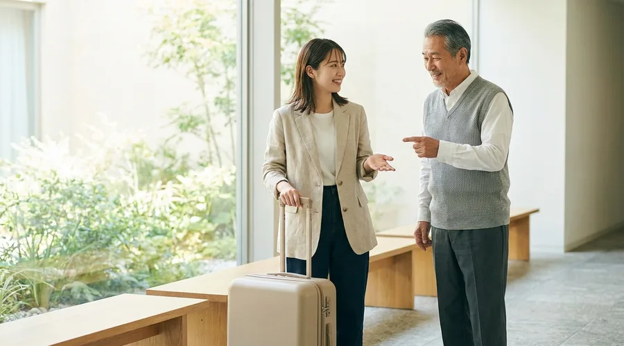 A traveller with a plain rolling suitcase asks directions with an open hand